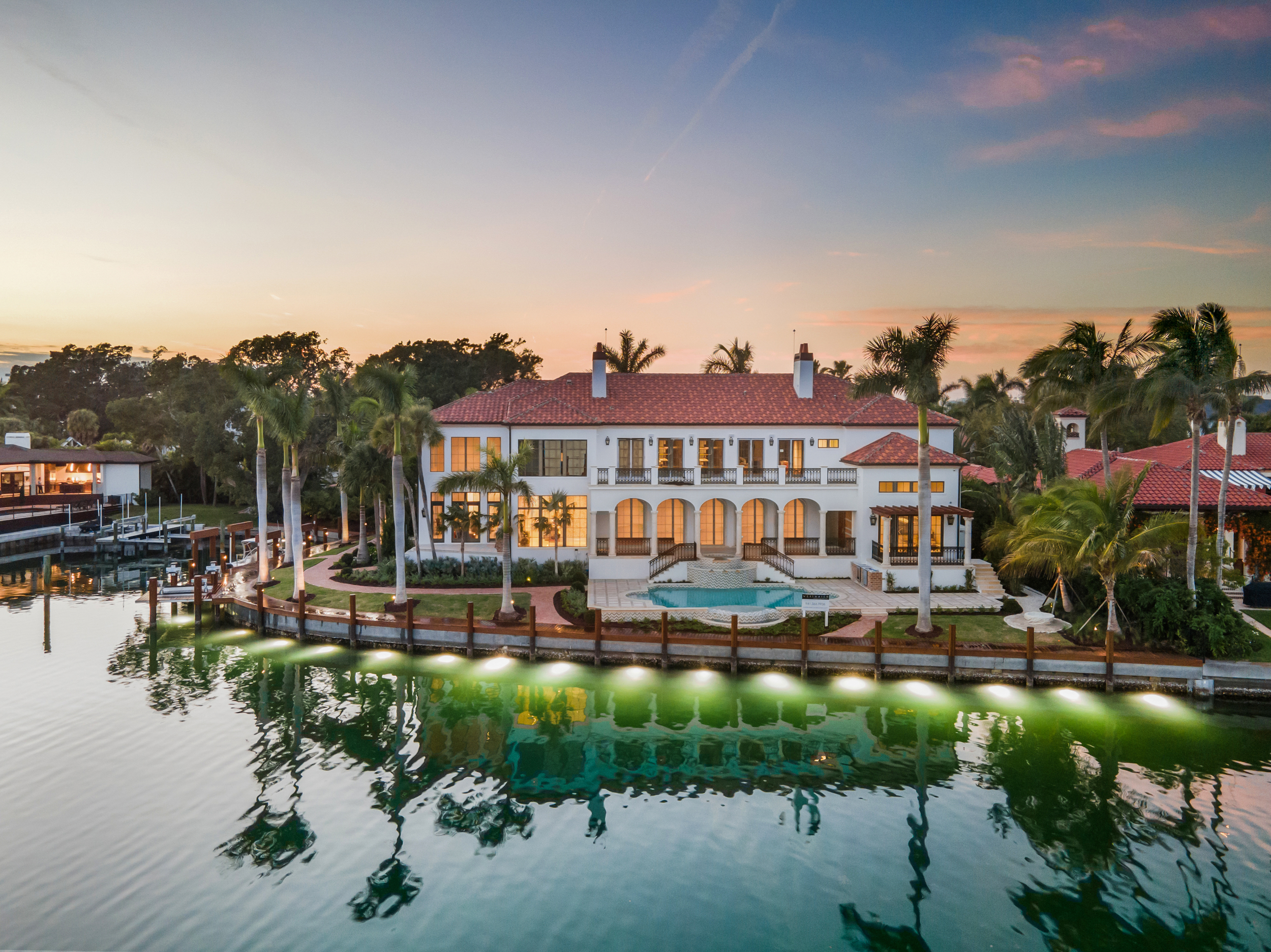 Luxury home with a custom boat dock and lift, landscaping, and pool in Sarasota, Florida.