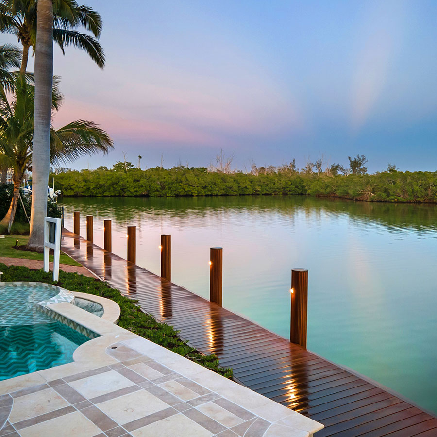 Luxury home with a custom boat dock and lift, landscaping, and pool in Sarasota, Florida.